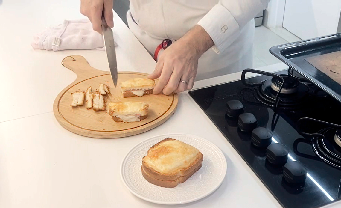 Chef Lionel Ortega preparando um croque-monsieur em cozinha profissional