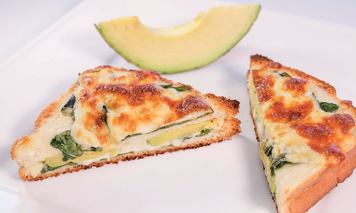 Croque-monsieur gratinado cortado em triângulos com queijo dourado e folhas verdes